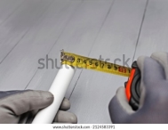 the plumber measures the length of a plastic pipe with a tape measure